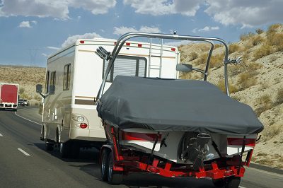An rv towing a boat on a recreational road trip.