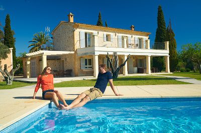 young couple enjoying first warm days of spanish spring at swimmingpool of their finca house